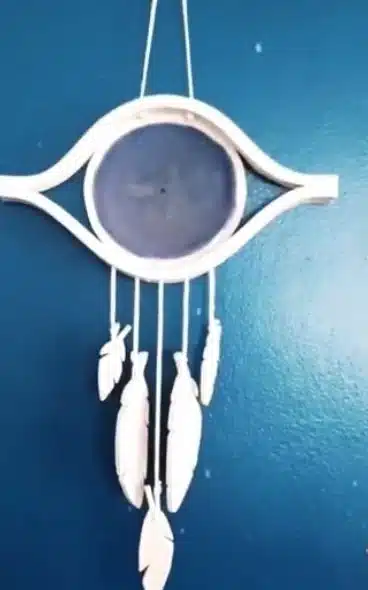Attrape-rêve œil de protection sur un mur bleu Attrape-rêve en céramique avec œil de protection bleu et plumes en grès, suspendu sur un mur bleu